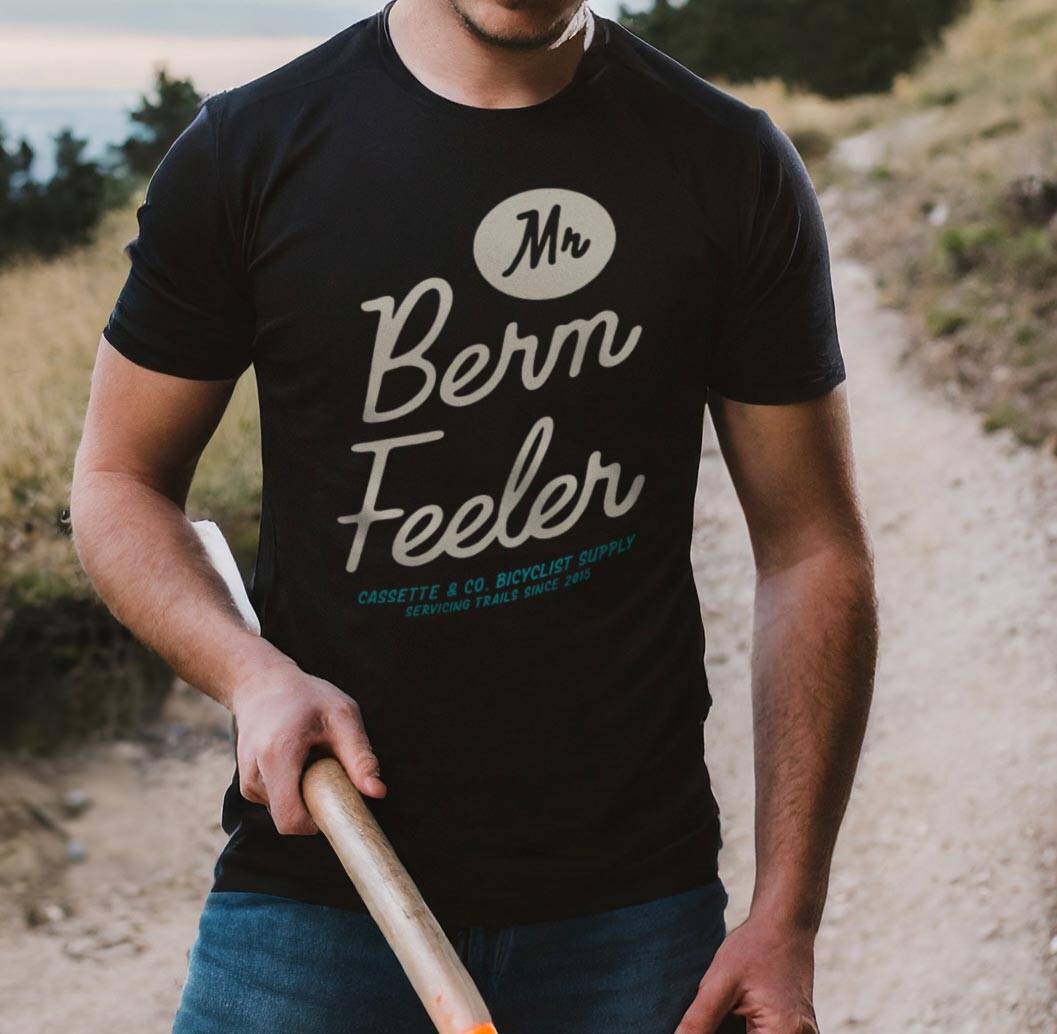 man with shovel working on mountain bike trail wearing the mr berm feeler t-shirt in black