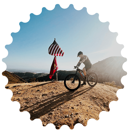 mountain biker at the top of The Luge trail next to American flag