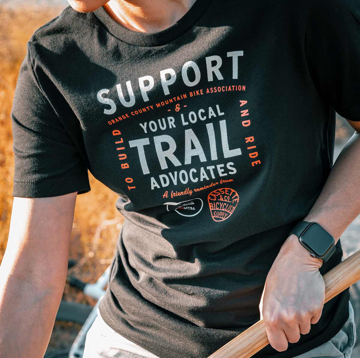 person wearing ocmtba tee while working on trail